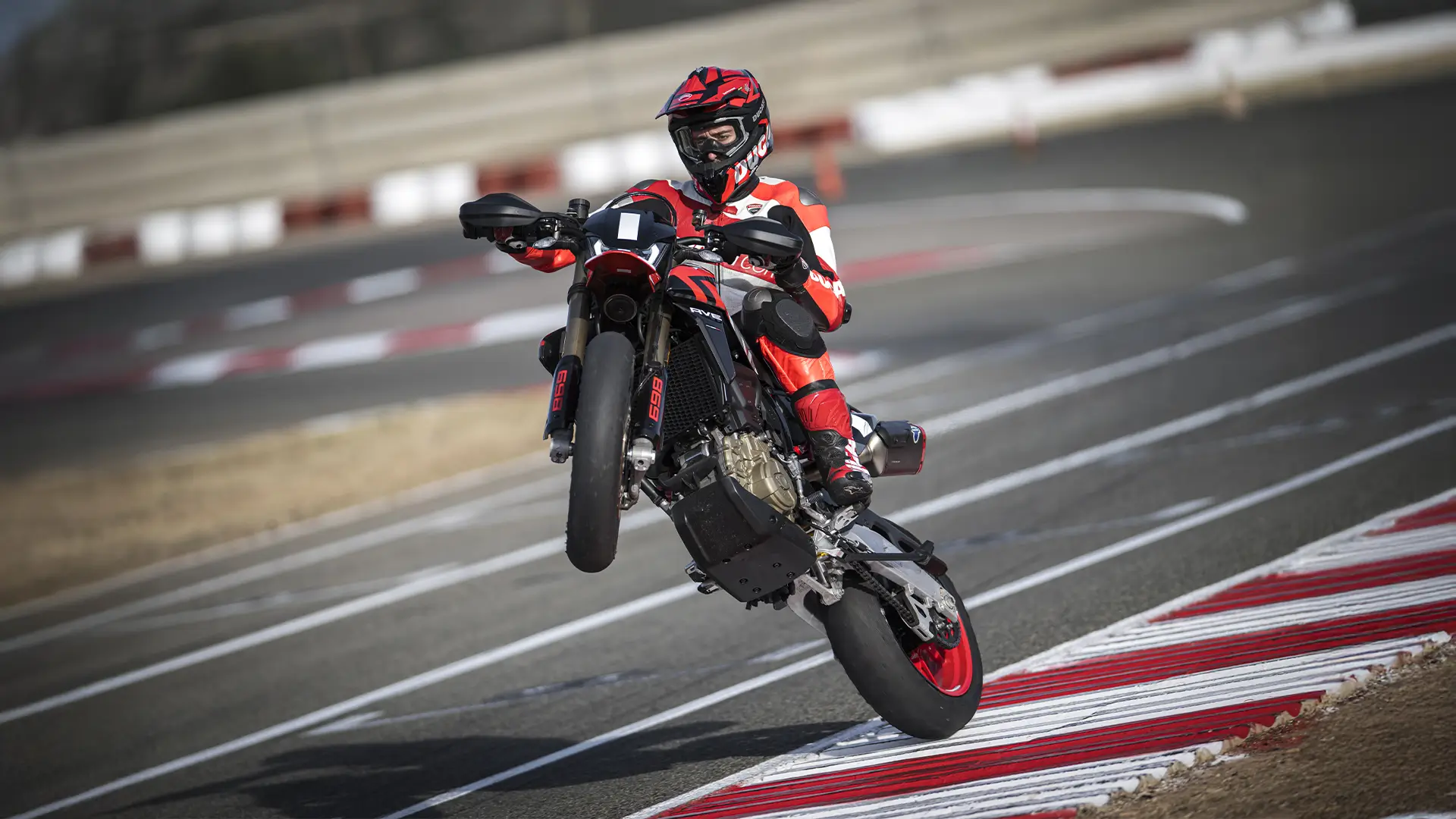 Ein Motorradfahrer macht einen Wheelie auf einer Rennstrecke mit einer Ducati Hypermotard.