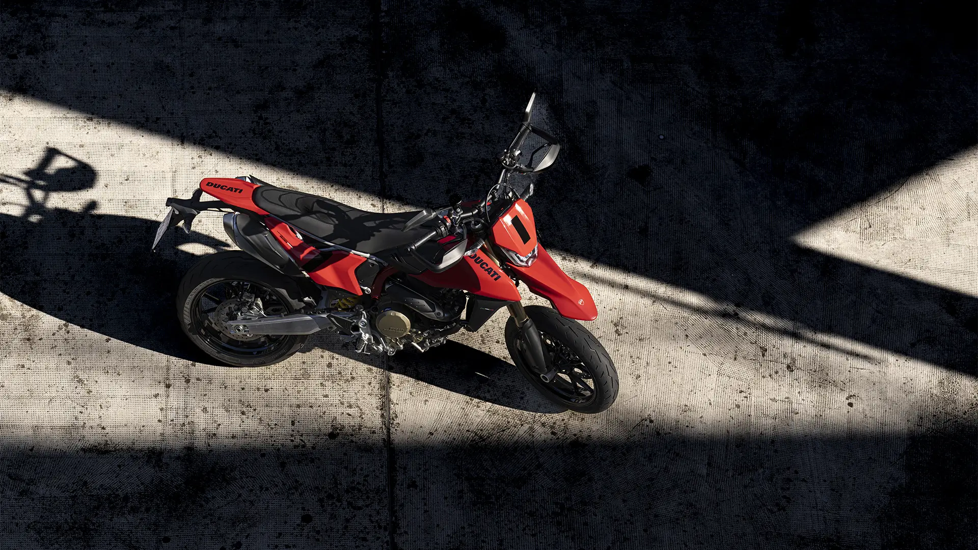 Ein rotes Ducati-Motorrad steht auf einem Betonboden im Schatten.