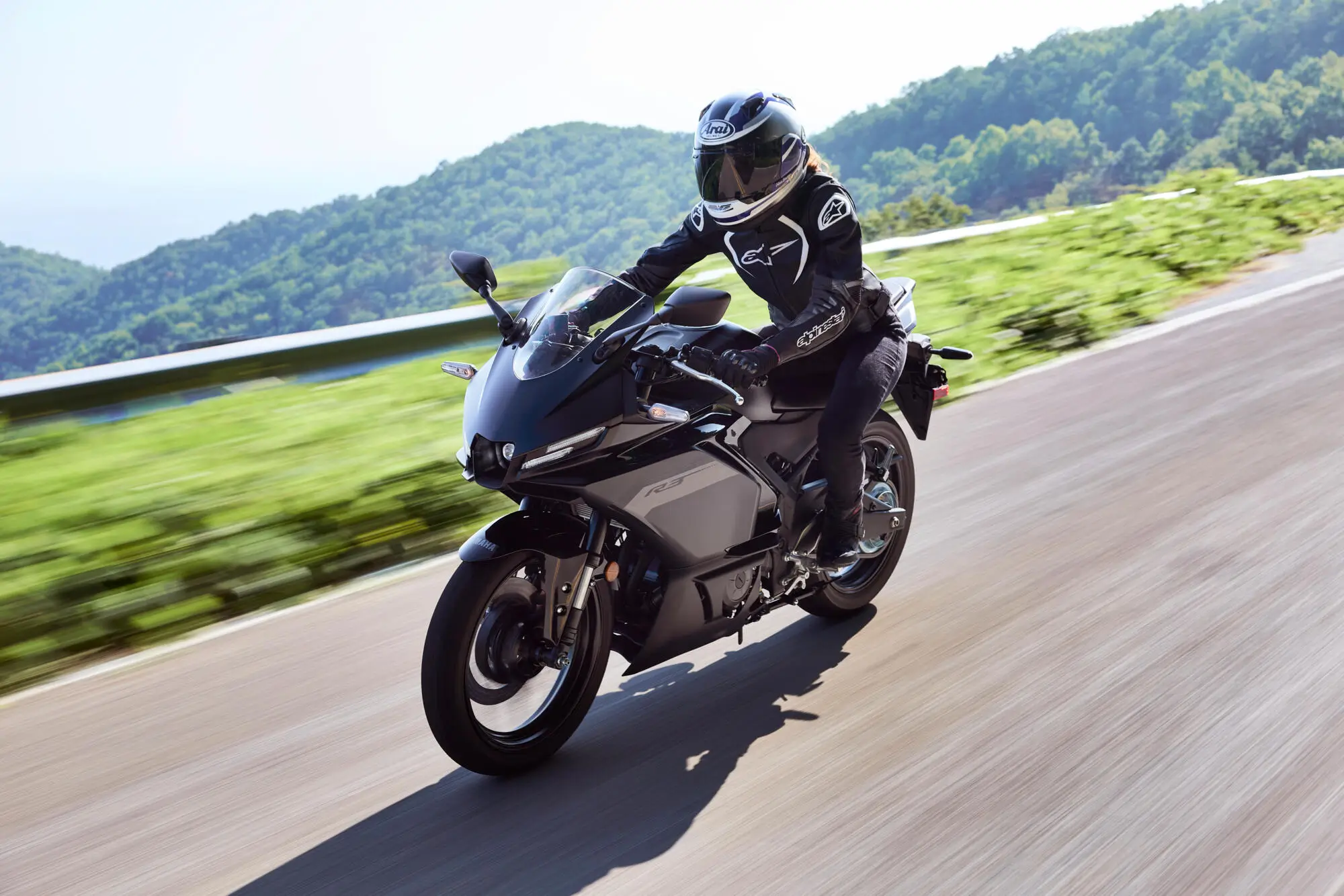 Ein Motorradfahrer fährt eine Yamaha YZF-R320 in schwarzer Farbe auf einer Landstraße.