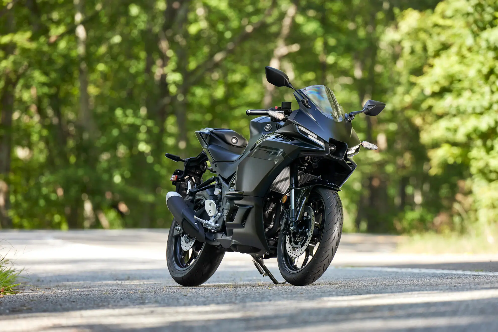 Ein schwarzes Yamaha YZF-R320 Motorrad steht auf einer Straße im Wald.