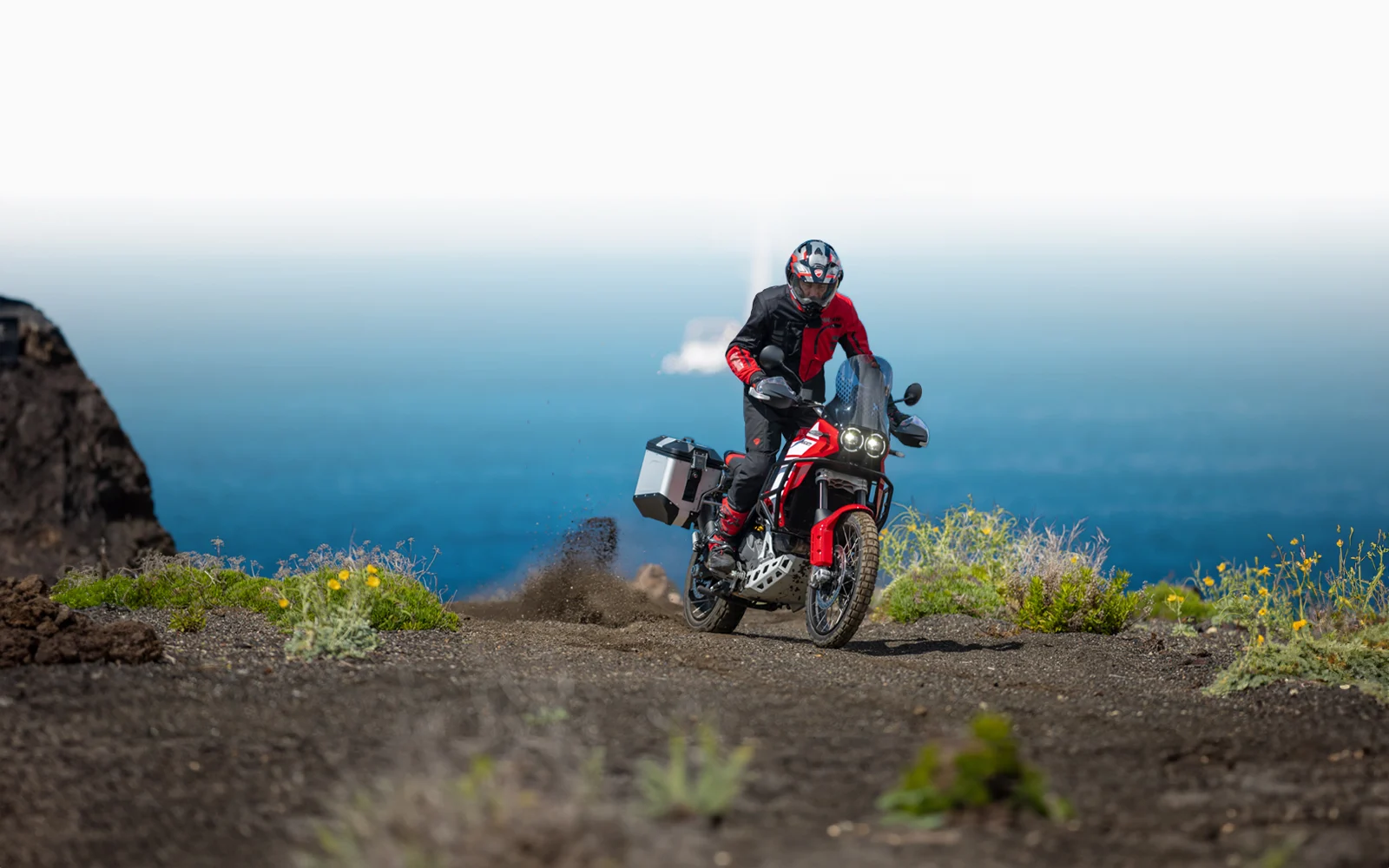 Ein Motorradfahrer fährt eine Ducati DesertX über eine staubige Offroad-Strecke.