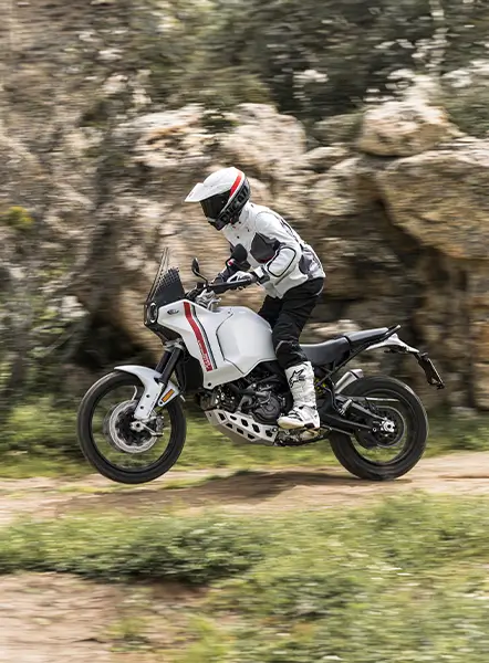 Ein Motorradfahrer fährt eine Ducati DesertX auf einem unbefestigten Weg.