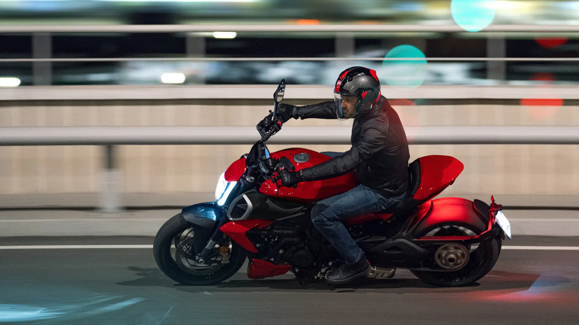 Ein Mann fährt eine rote Ducati Diavel V4 auf einer Straße.