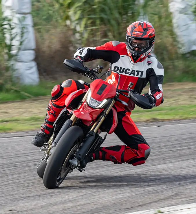 Ducati-Hypermotard-Mono-DWP24-Elettronica-carousel-imgtxt-677x740-02 Ein Motorradfahrer in Ducati-Rennkleidung fährt eine Ducati Hypermotard auf einer Rennstrecke.