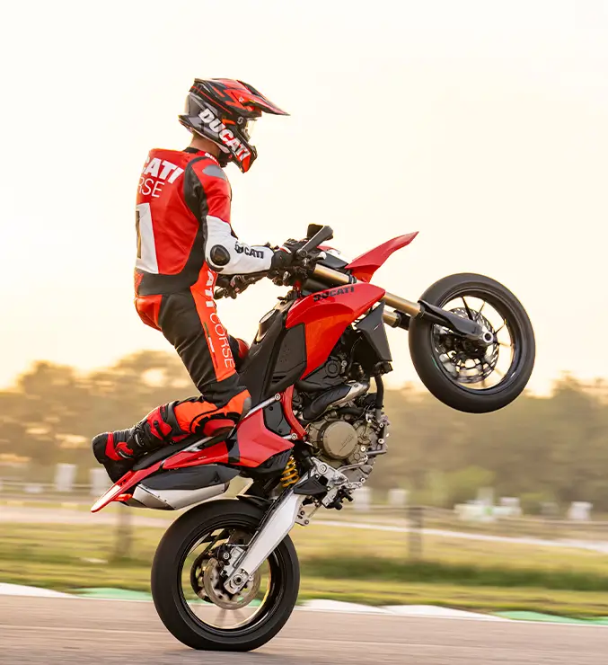 Ein Motorradfahrer macht einen Wheelie auf einer Ducati Hypermotard.