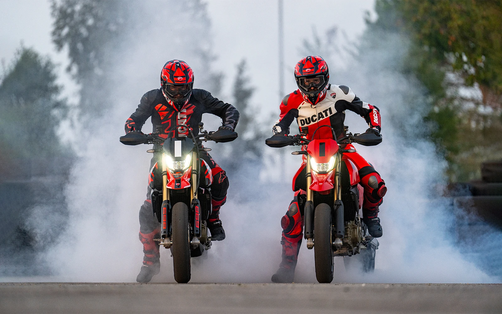 Zwei Personen machen einen Burnout auf Ducati Hypermotard Motorrädern.