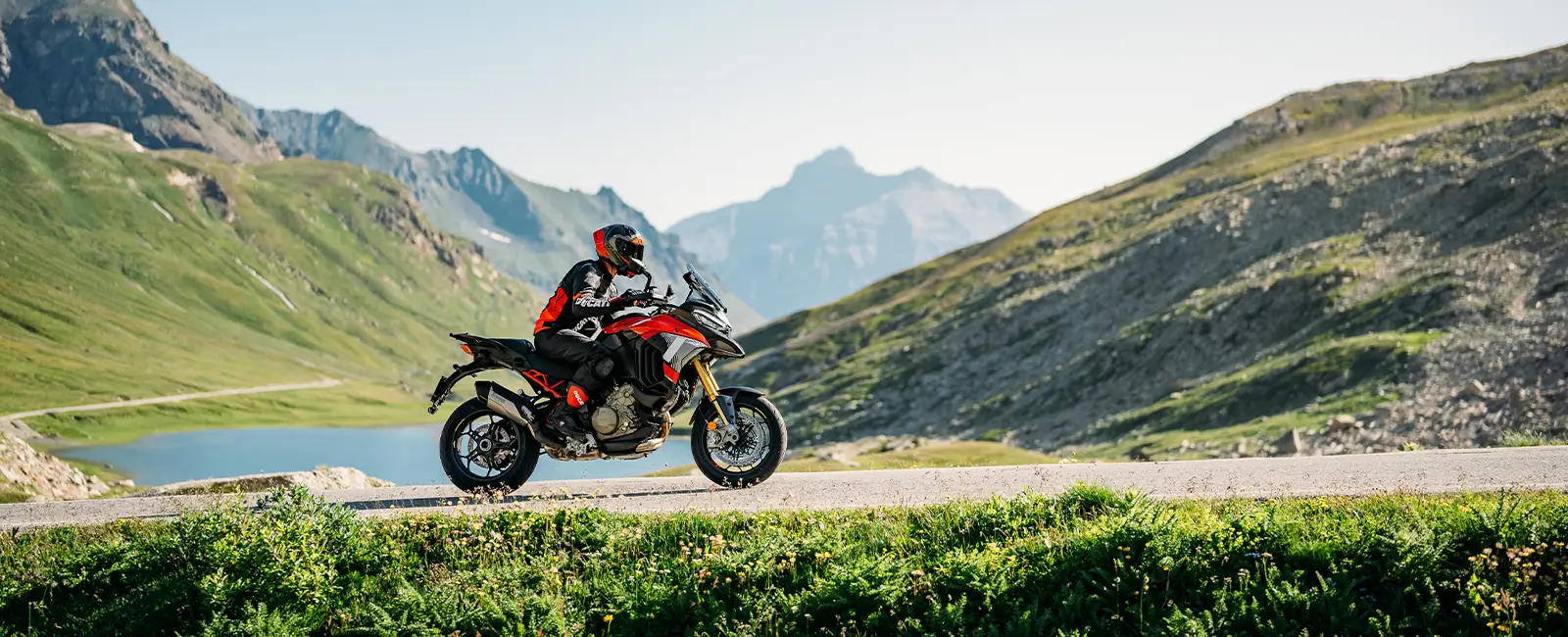 Ein Motorradfahrer auf einer Ducati Multistrada V4 fährt durch eine bergige Landschaft.