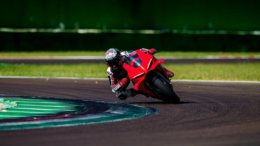 Ein Motorradfahrer auf einer roten Ducati Panigale V4 neigt sich in eine Kurve auf einer Rennstrecke.