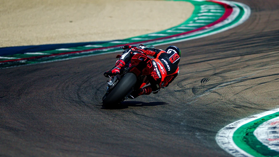 Ein Motorradfahrer auf einer Ducati Panigale V4 fährt in Schräglage durch eine Rennstreckenkurve.