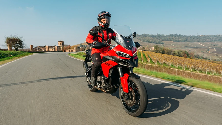 Ein Motorradfahrer fährt eine rote Ducati Multistrada V2 auf einer Landstraße.