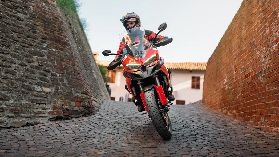 Ein Motorradfahrer auf einer Ducati Multistrada V2 fährt durch eine enge, gepflasterte Gasse.