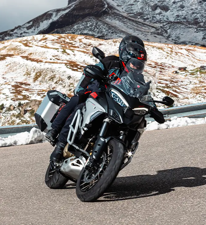Ducati-Multistrada-V4-Rally-MY23-tech-spec-carousel-imgtxt-02-677x740 Motorradfahrer auf einer Ducati Multistrada V4 Rally fährt auf einer kurvigen Bergstraße.