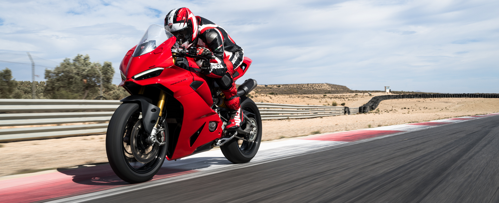 Ducati-Panigale-V2-V2S-Overview-carousel-hero-link-1600x650-04 Ein Motorradfahrer fährt eine rote Ducati Panigale V2 auf einer Rennstrecke.