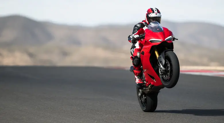 Ein Motorradfahrer macht einen Wheelie auf einer Ducati Panigale V2 auf einer Rennstrecke.