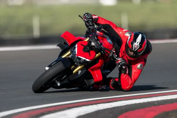 Ducati-Streetfighter-V4-DWP25-overview-carousel-hero-link-1600x650-02-2e4mtaz170d1q0q Ein Motorradfahrer in roter Schutzkleidung fährt eine Ducati Streetfighter V4 in starker Schräglage auf einer Rennstrecke.