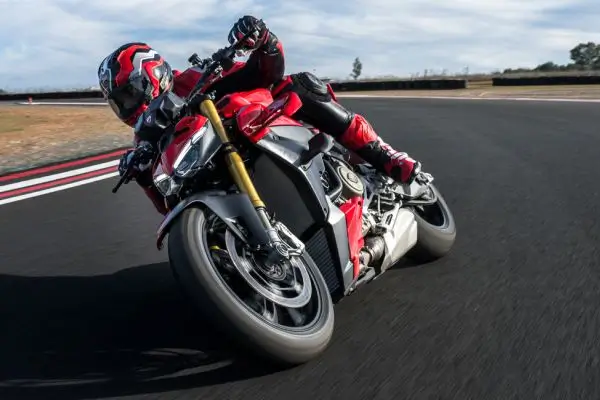 Ducati-Streetfighter-V4-DWP25-overview-carousel-hero-link-1600x650-03-9atkrbgncacah3d Ein Motorradfahrer auf einer Ducati Streetfighter V4 legt sich in eine Kurve auf einer Rennstrecke.