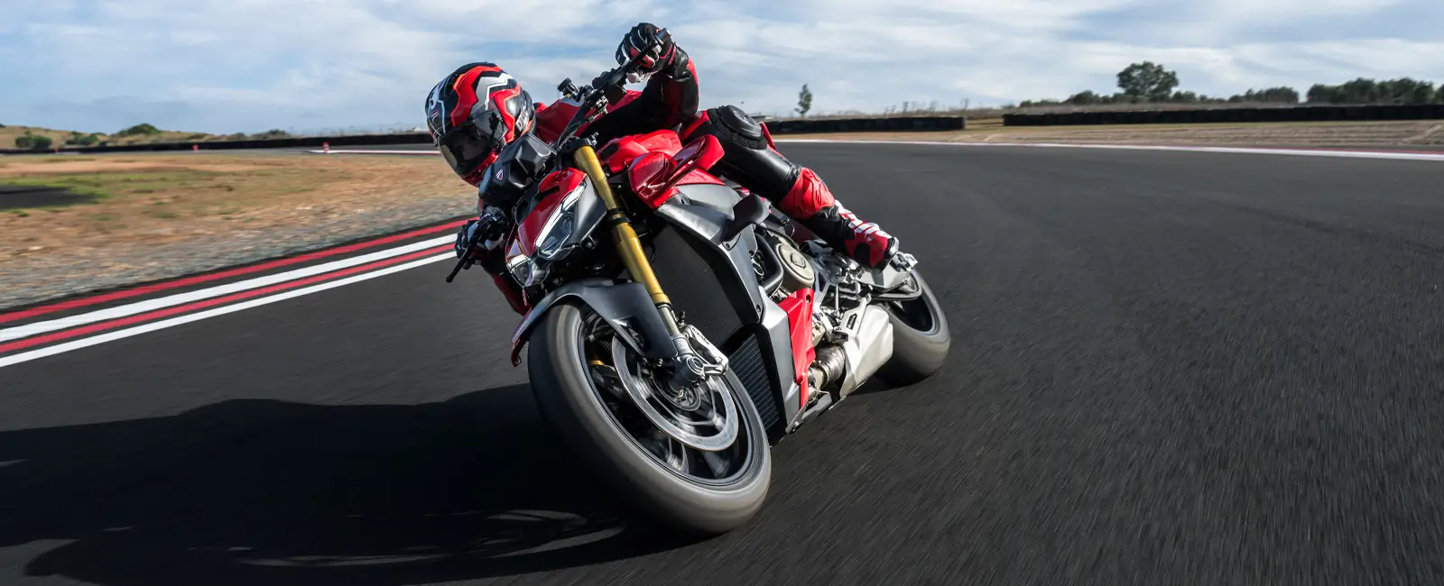 Ducati-Streetfighter-V4-DWP25-overview-carousel-hero-link-1600x650-03 Motorradfahrer auf einer Ducati Streetfighter V4 in einer Kurve auf der Rennstrecke.