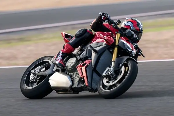 Ducati-Streetfighter-V4-DWP25-overview-carousel-hero-link-1600x650-04-2xha1k3br1gxnkt Ein Motorradfahrer auf einer Ducati Streetfighter V4 fährt in Schräglage auf einer Rennstrecke.