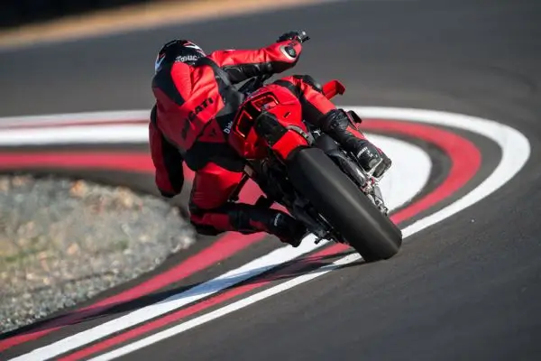 Ducati-Streetfighter-V4-DWP25-overview-carousel-hero-link-1600x650-05-wny57ptesckmv31 Ein Fahrer in roter Schutzkleidung fährt eine Ducati Streetfighter V4 in Schräglage durch eine Kurve.