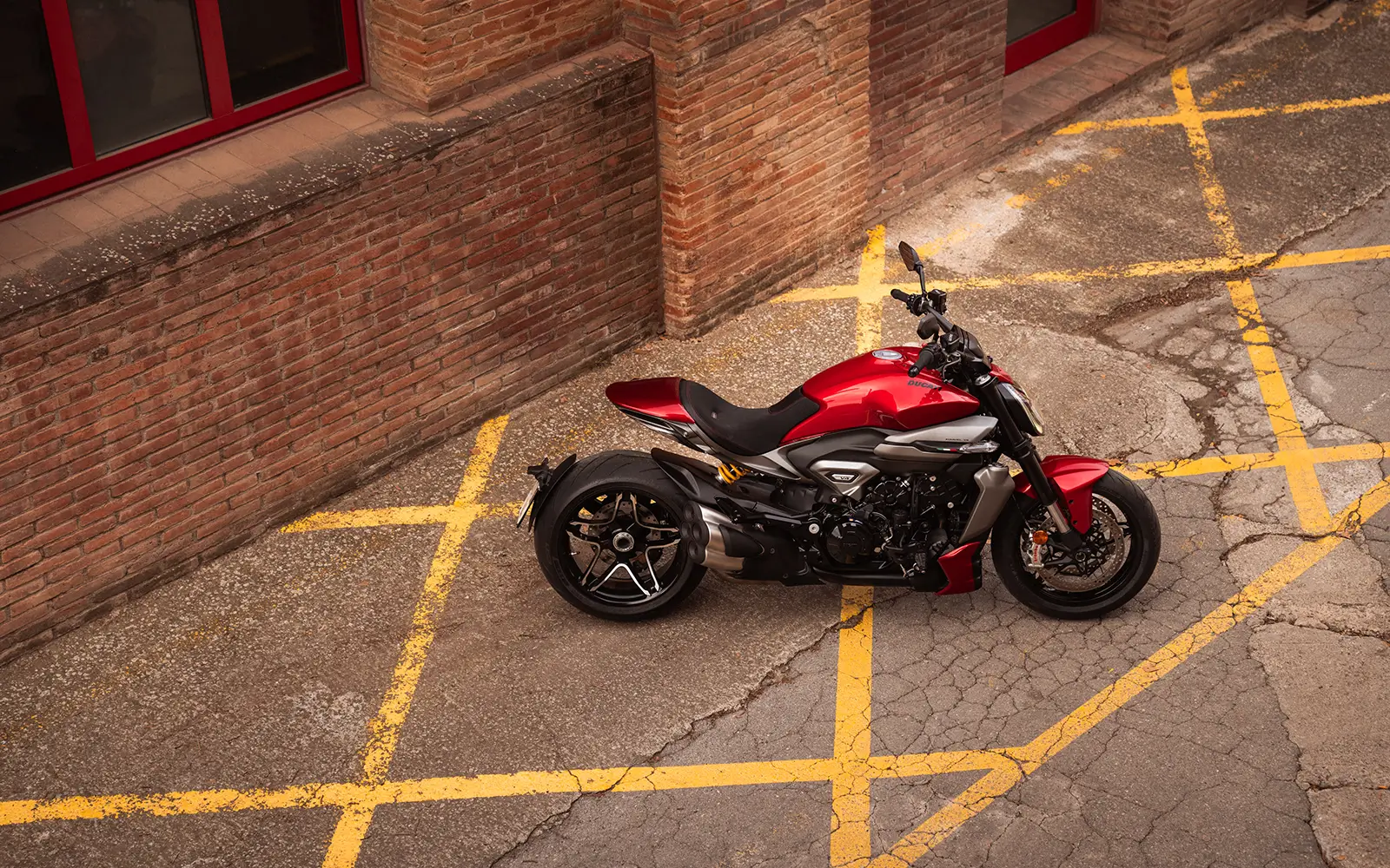 Ducati-XDiavel-V4-overview-hero-short-1600x1000 Rotes Ducati XDiavel V4 Motorrad steht auf einem gepflasterten Platz.