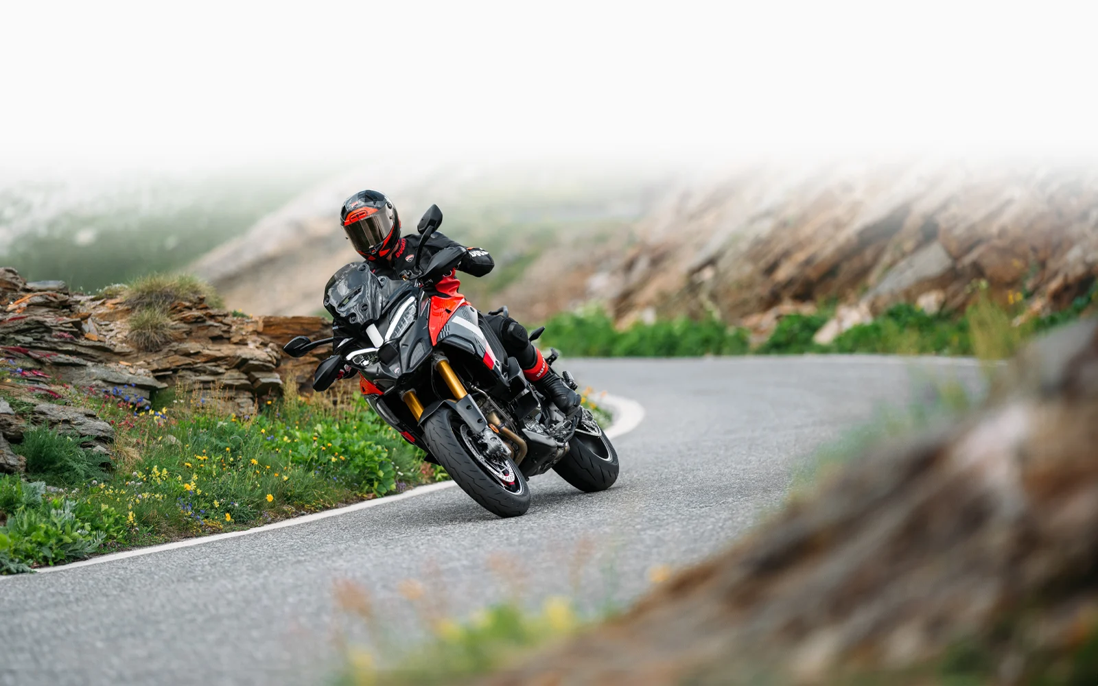 Ein Motorradfahrer fährt eine Ducati Multistrada V4 Pikes Peak auf einer kurvigen Bergstraße.