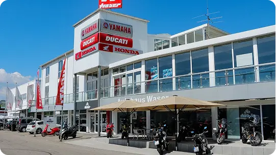 Motorradgeschäft mit den Marken Yamaha, Ducati und Honda, Motorräder vor dem Gebäude.