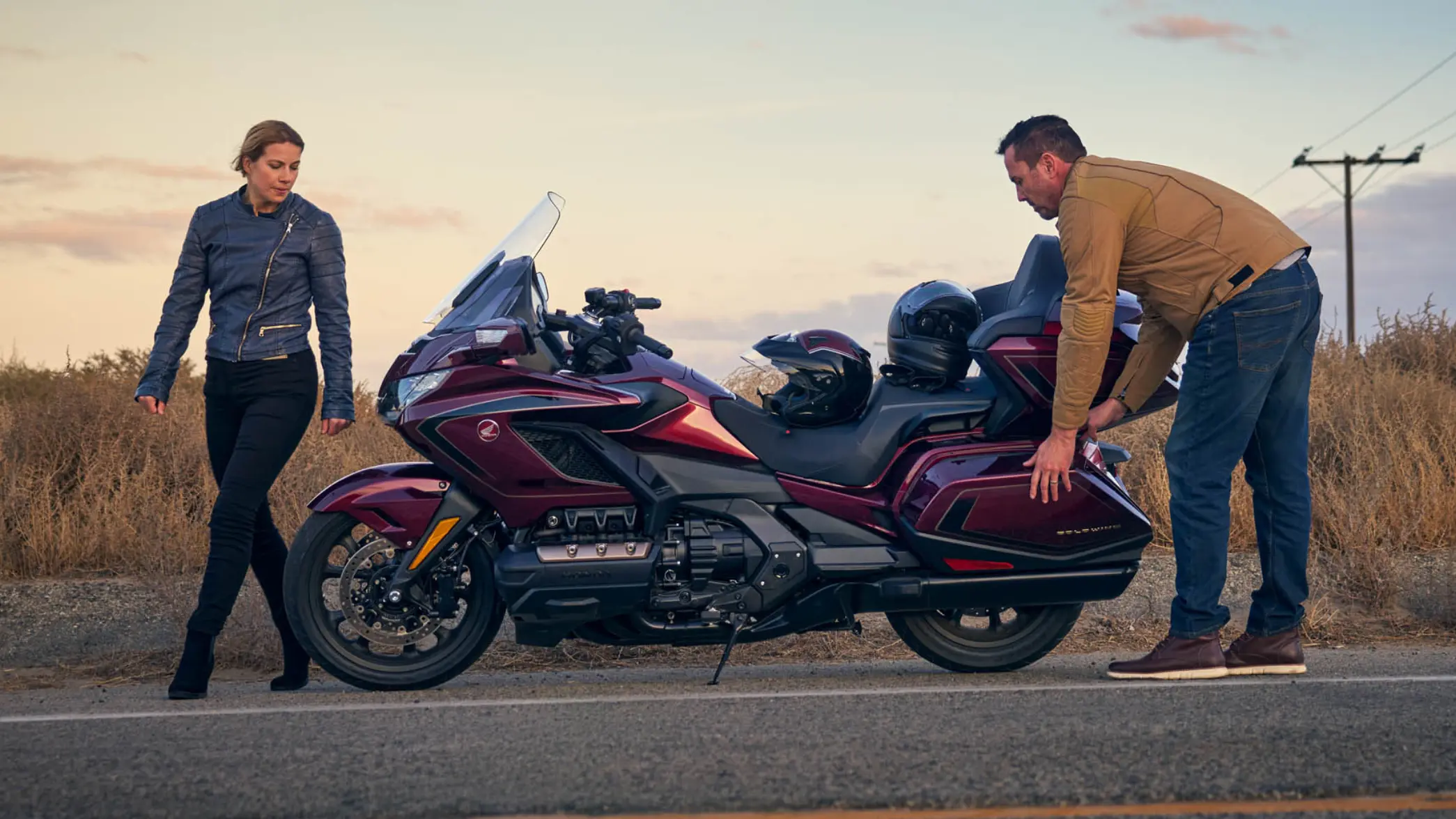 Eine Frau und ein Mann stehen neben einer Honda GL1800 GOLD WING TOUR auf einer Straße.