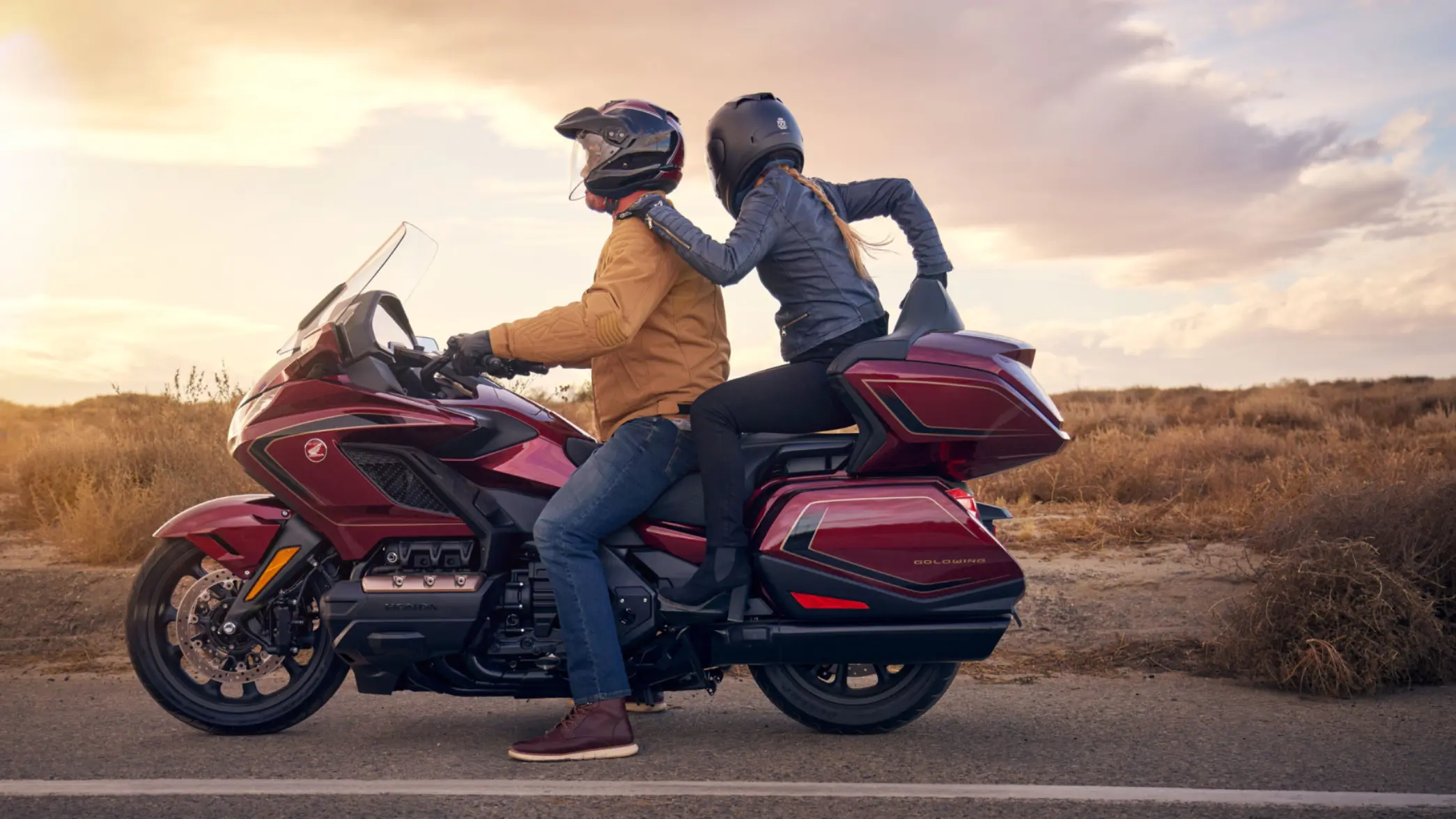 Zwei Personen fahren auf einem Honda Gold Wing Motorrad auf einer Landstraße.