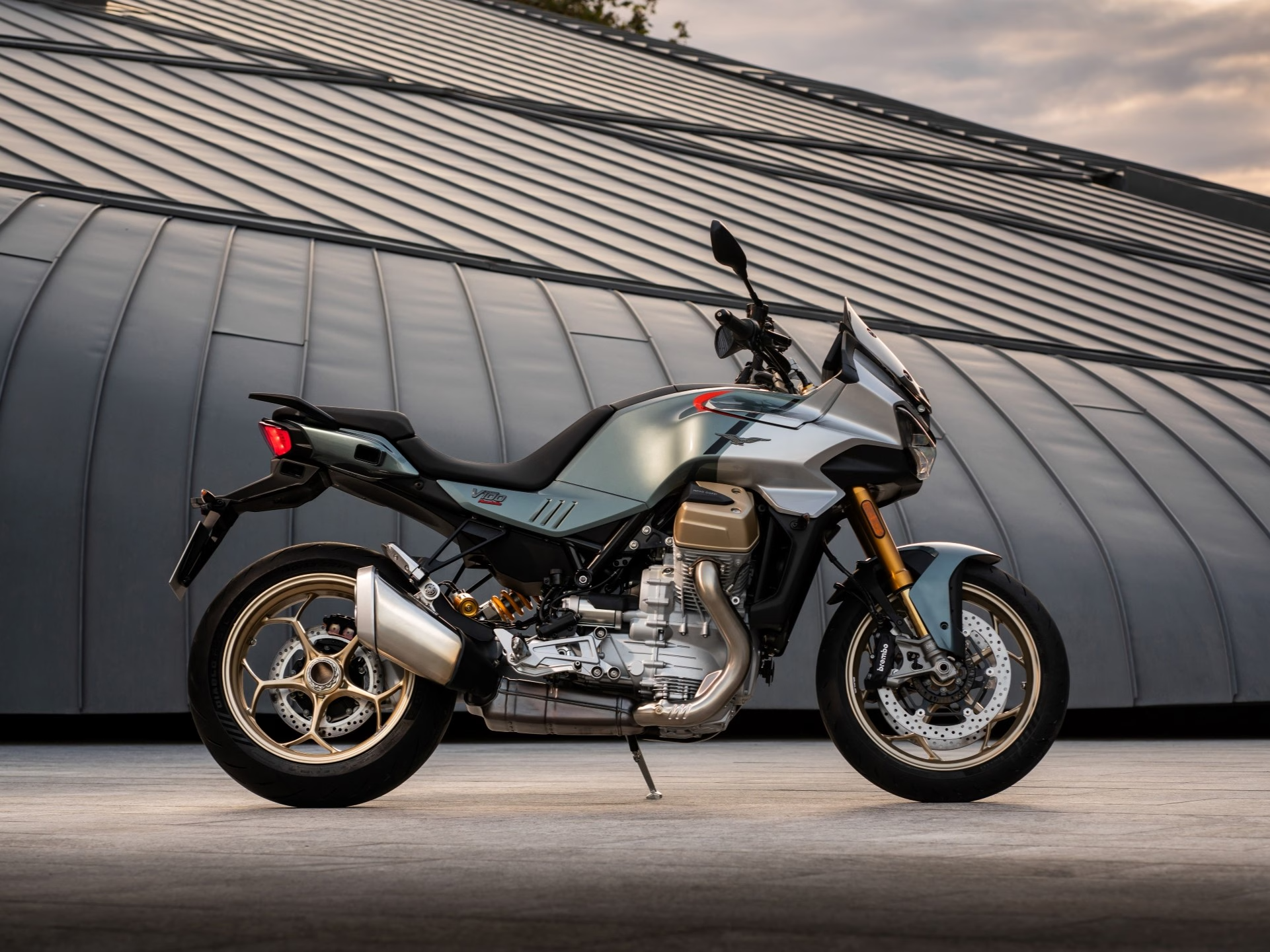 Ein silbernes Moto Guzzi Mandello S 1000 Motorrad steht vor einem modernen Gebäude.