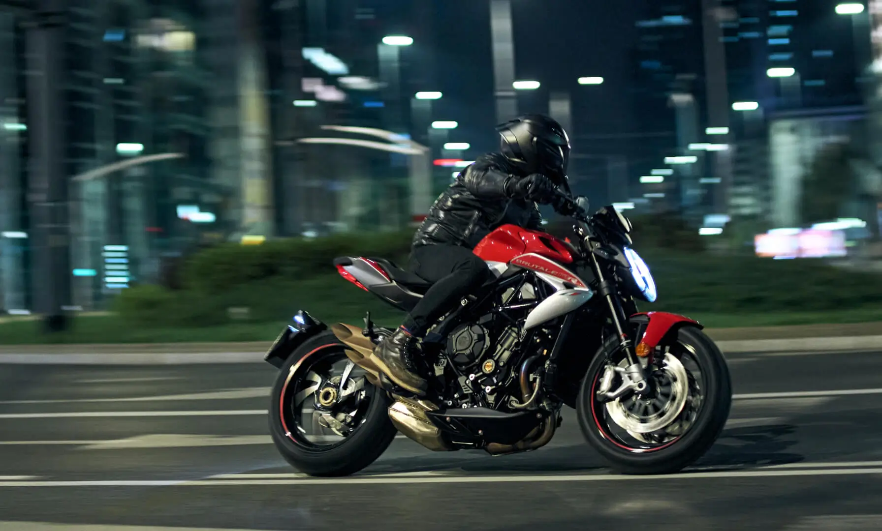 Motorradfahrer auf einer MV Agusta Brutale 800 fährt bei Nacht durch die Stadt.