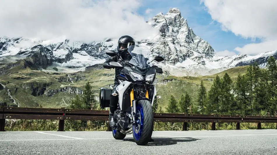 Ein Motorradfahrer auf einer Yamaha MT-09 Tracer GT fährt vor einer Schweizer Berglandschaft.