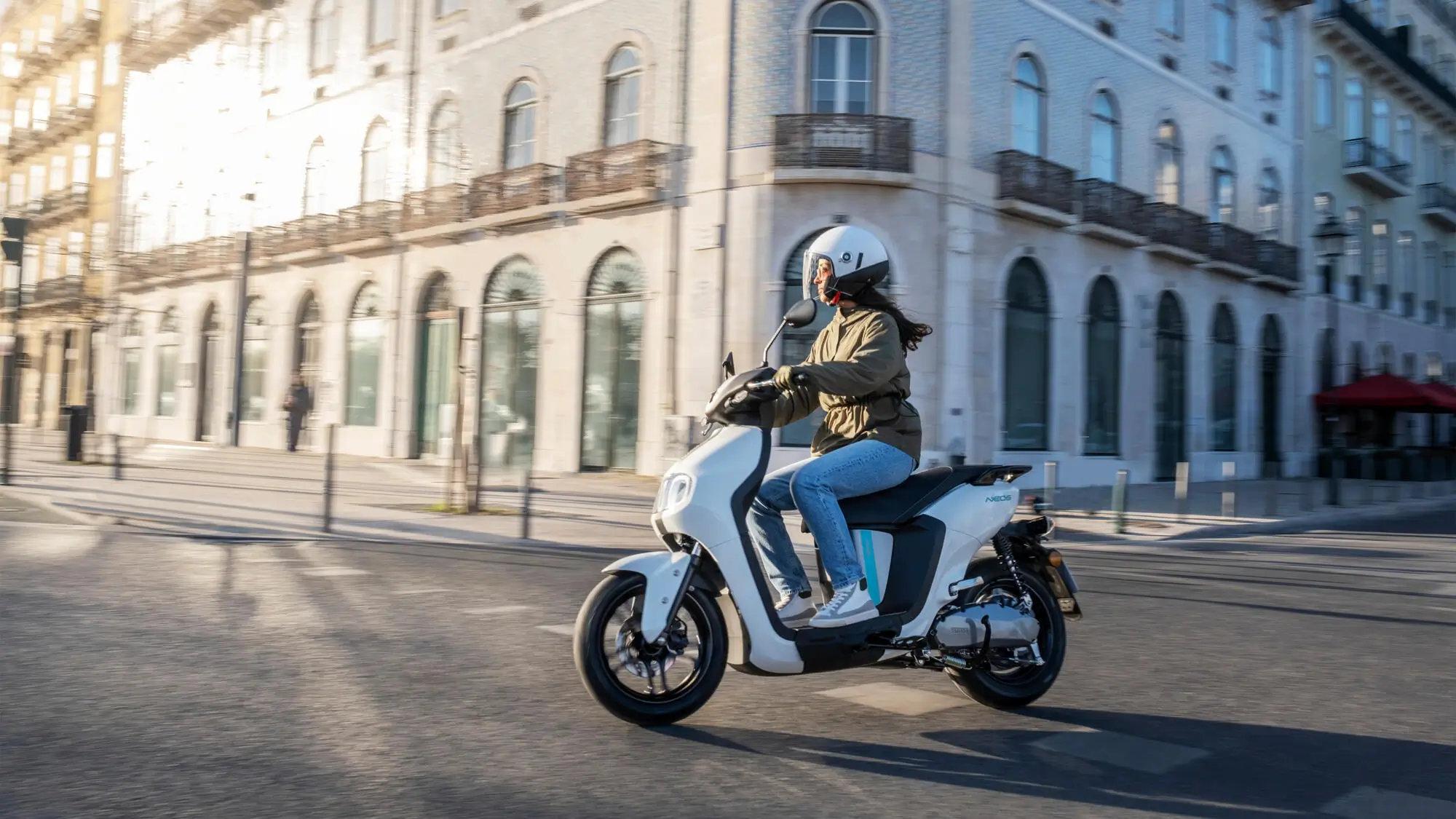 Eine Person fährt auf einem 2023 Yamaha NEOS Roller durch eine Stadt.