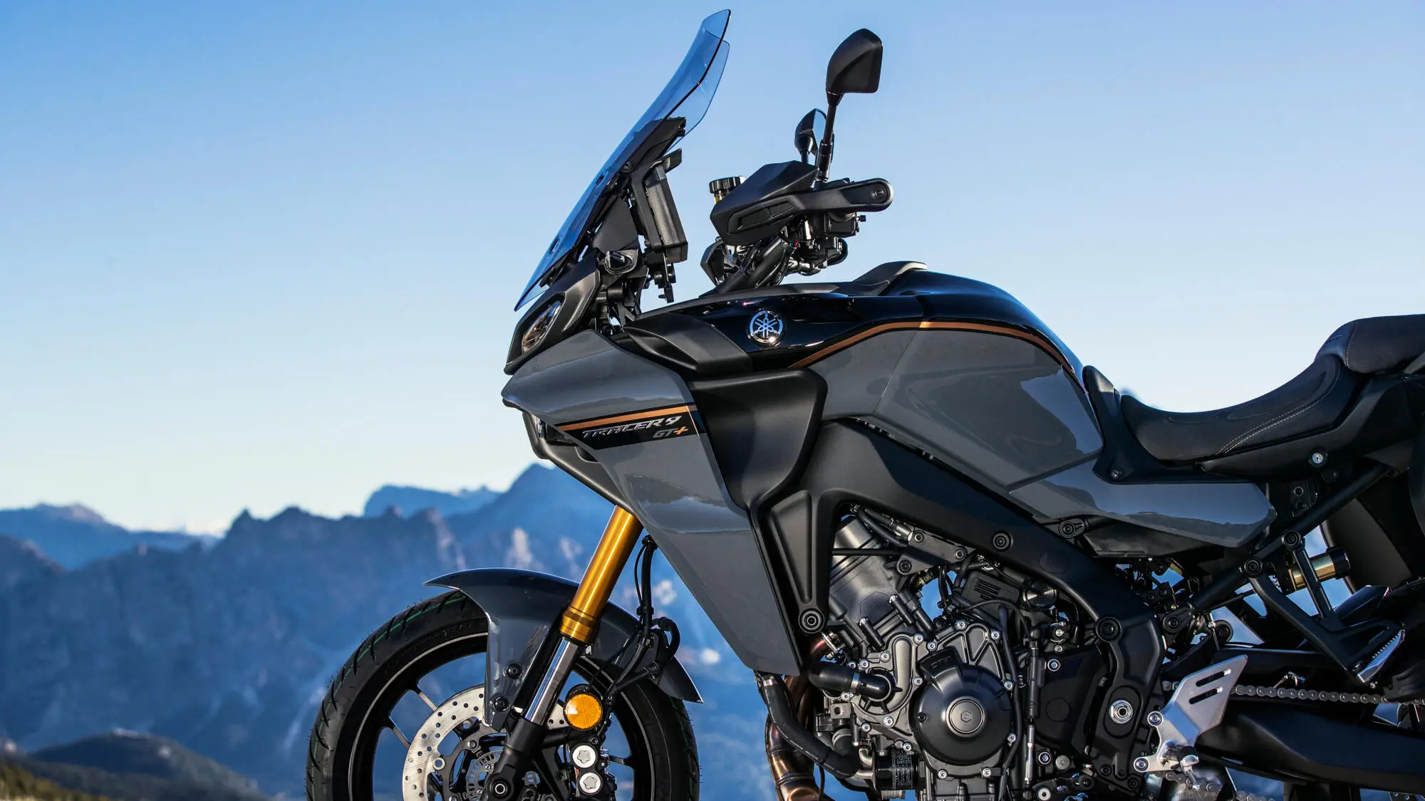 Ein graues 2024 Yamaha TRACER 9 GT+ Motorrad vor Bergkulisse.