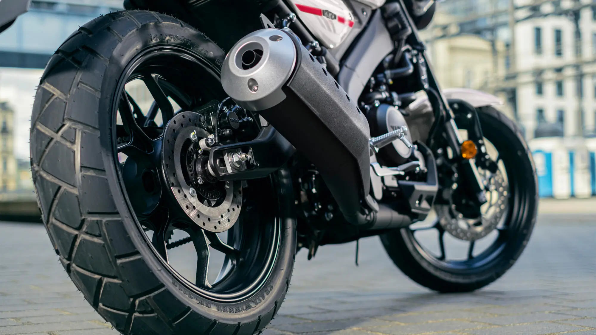 Nahaufnahme des Hinterrads und Auspuffs einer 2024 Yamaha XS125.