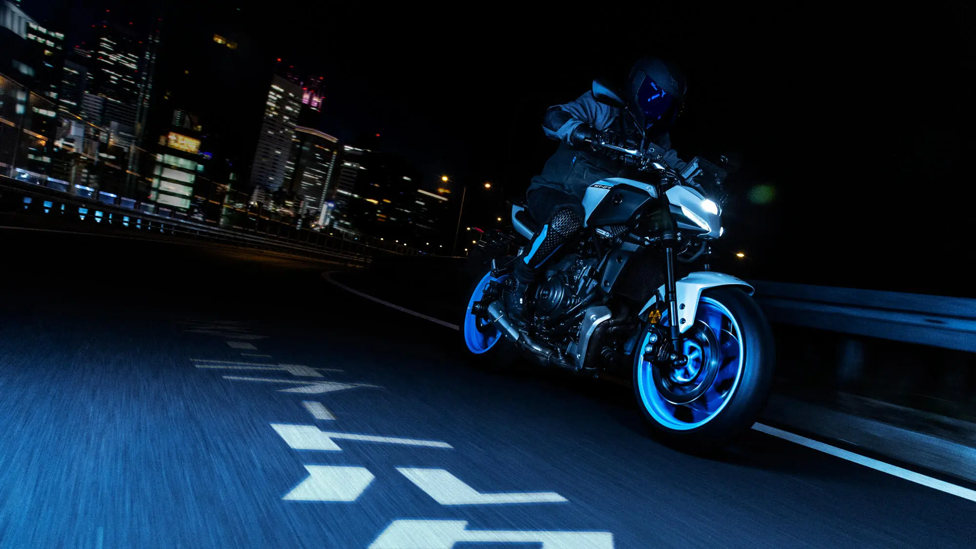 Ein Motorradfahrer fährt eine Yamaha MT-07 bei Nacht durch eine Stadt.