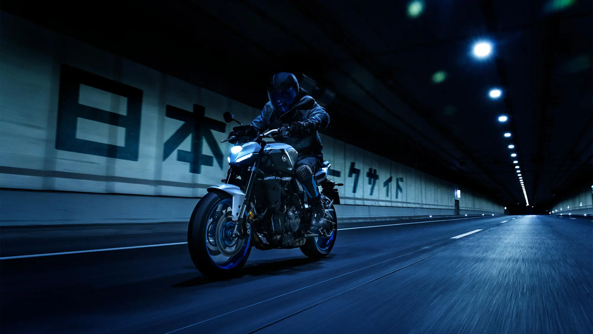 Ein Motorradfahrer fährt eine 2025 Yamaha MT-07AS durch einen beleuchteten Tunnel.