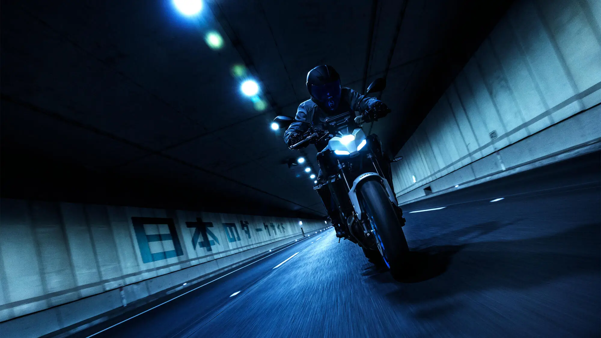 Ein Motorradfahrer fährt eine Yamaha MT-07 durch einen beleuchteten Tunnel.