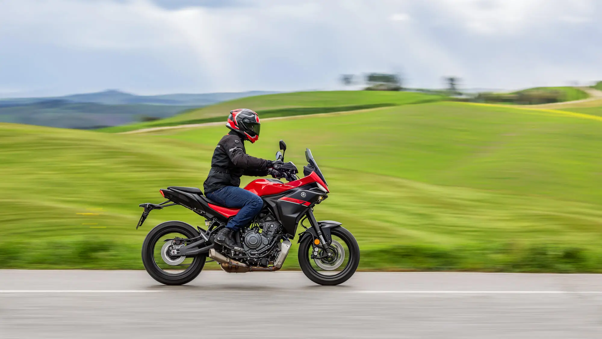 Eine Person fährt eine rote Yamaha MT-07 TR auf einer Landstraße.