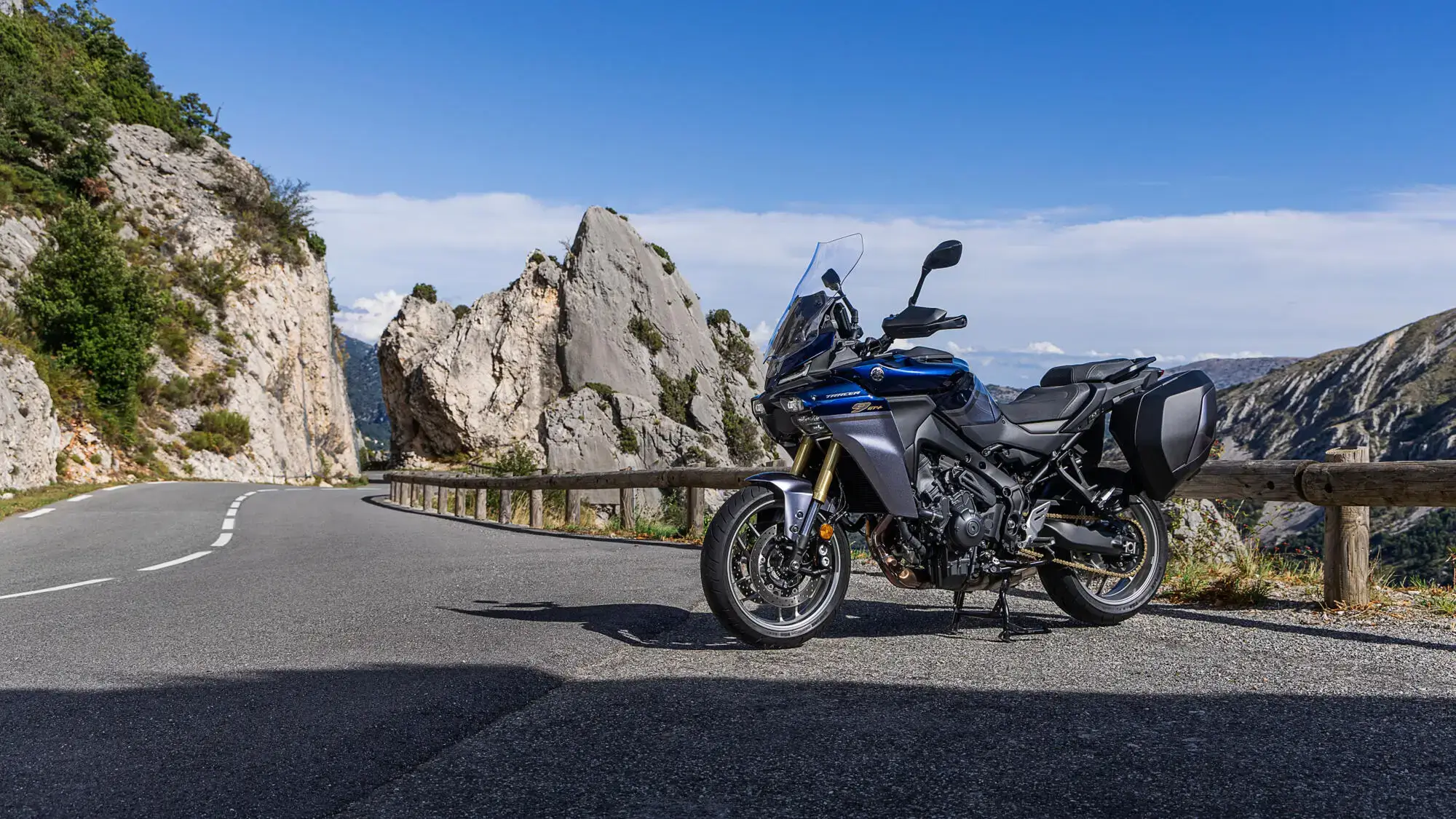 2025-Yamaha-MT09ATRDXCS-EU-Cobalt_Blue-Static-001-03 Yamaha TRACER 9 GT+ Motorrad steht auf einer kurvigen Bergstraße.