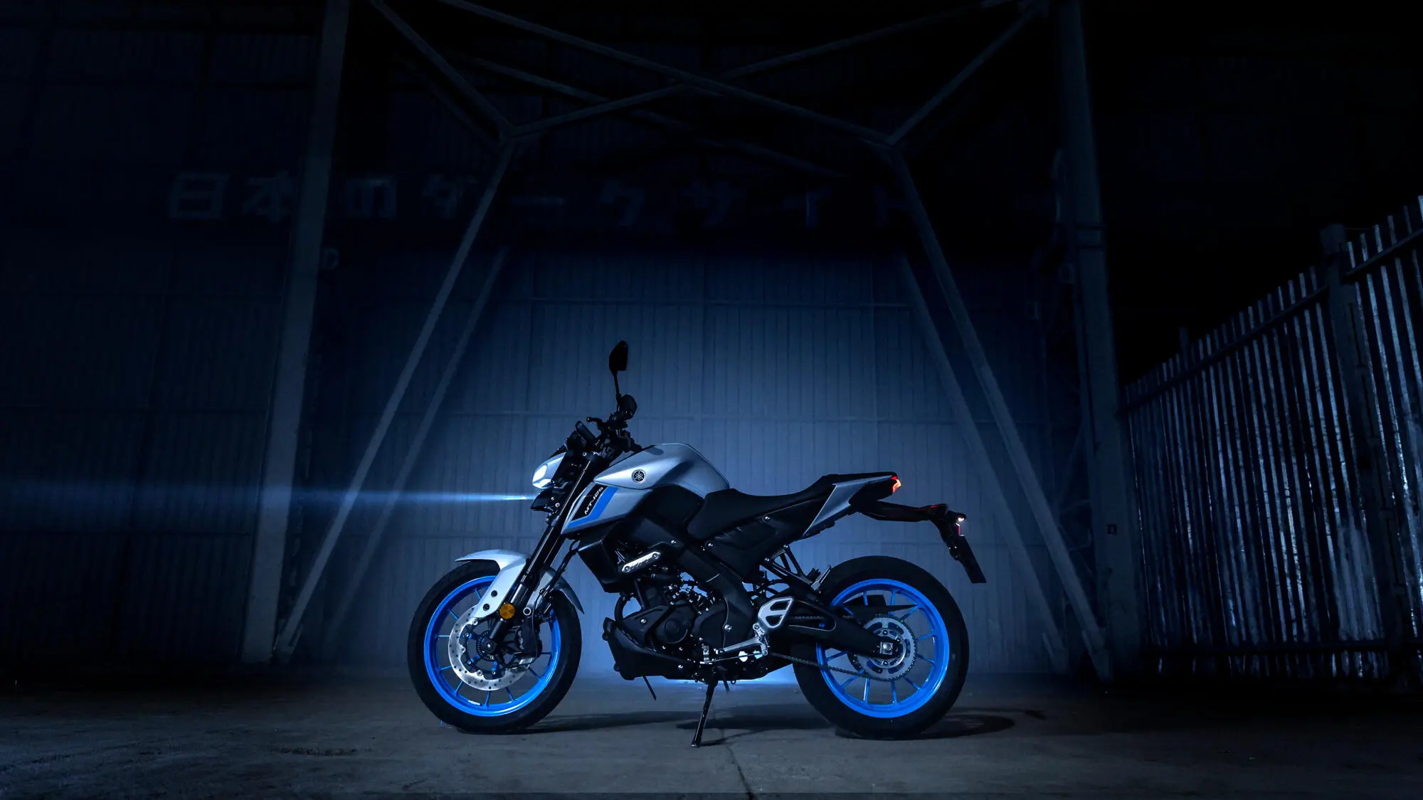 Ein Yamaha MT125A Motorrad in einer dunklen Umgebung mit blauen Felgen.