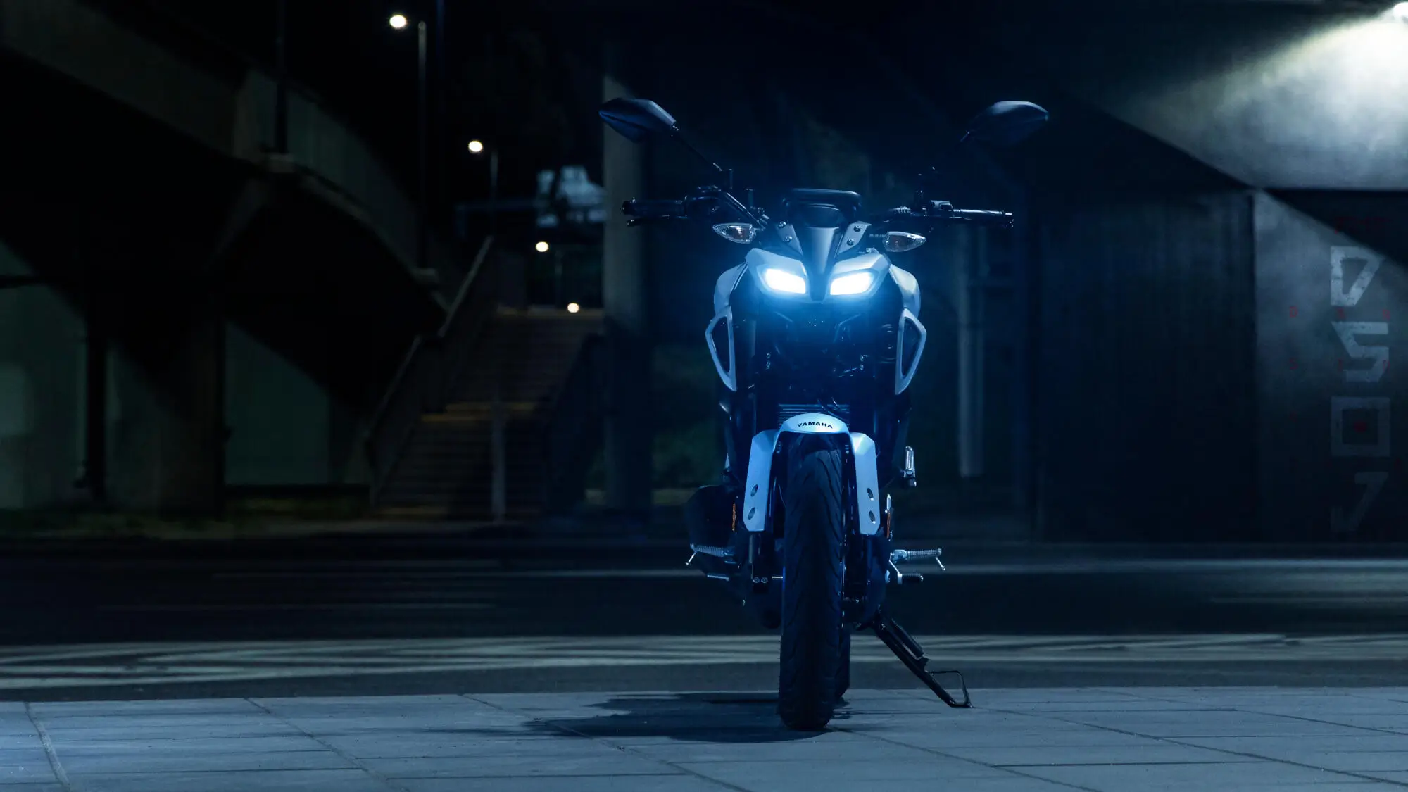 Yamaha MT-125 Motorrad bei Nacht mit eingeschaltetem Scheinwerfer.