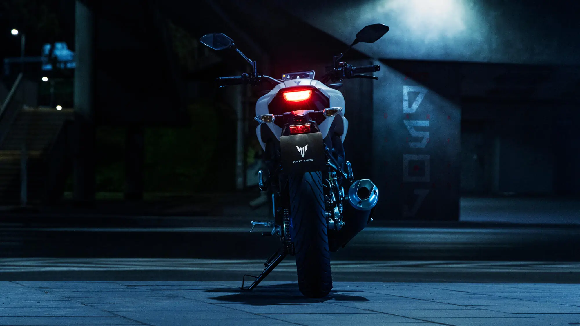 Rückansicht eines stehenden Yamaha MT-125 Motorrads in einer urbanen Umgebung bei Nacht.