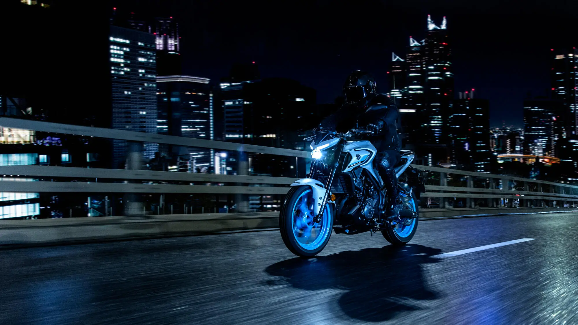 Ein Motorradfahrer fährt nachts eine Yamaha MT320 durch eine beleuchtete Stadt.