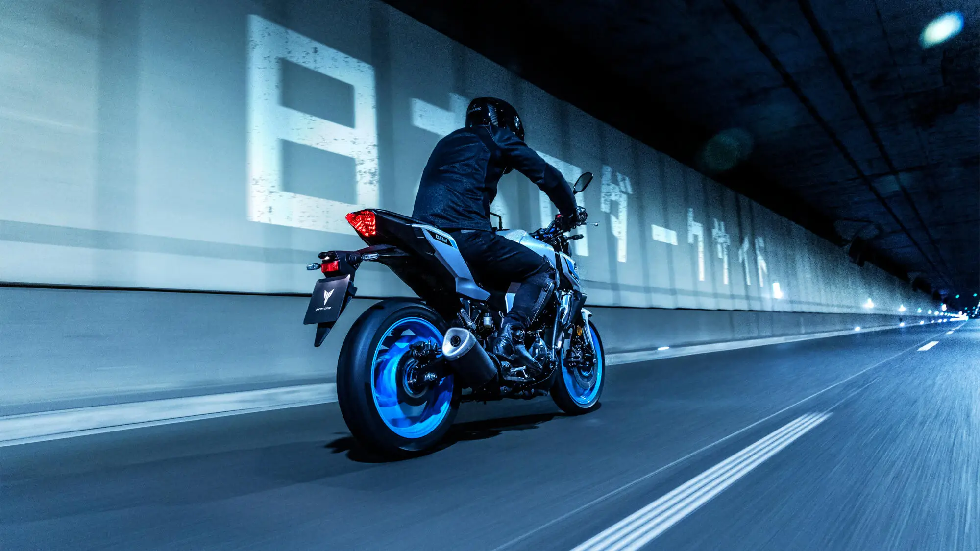 2025-Yamaha-MT320-EU-Ice_Storm-Action-009-03 Ein Motorradfahrer fährt eine 2025 Yamaha MT320 durch einen beleuchteten Tunnel.