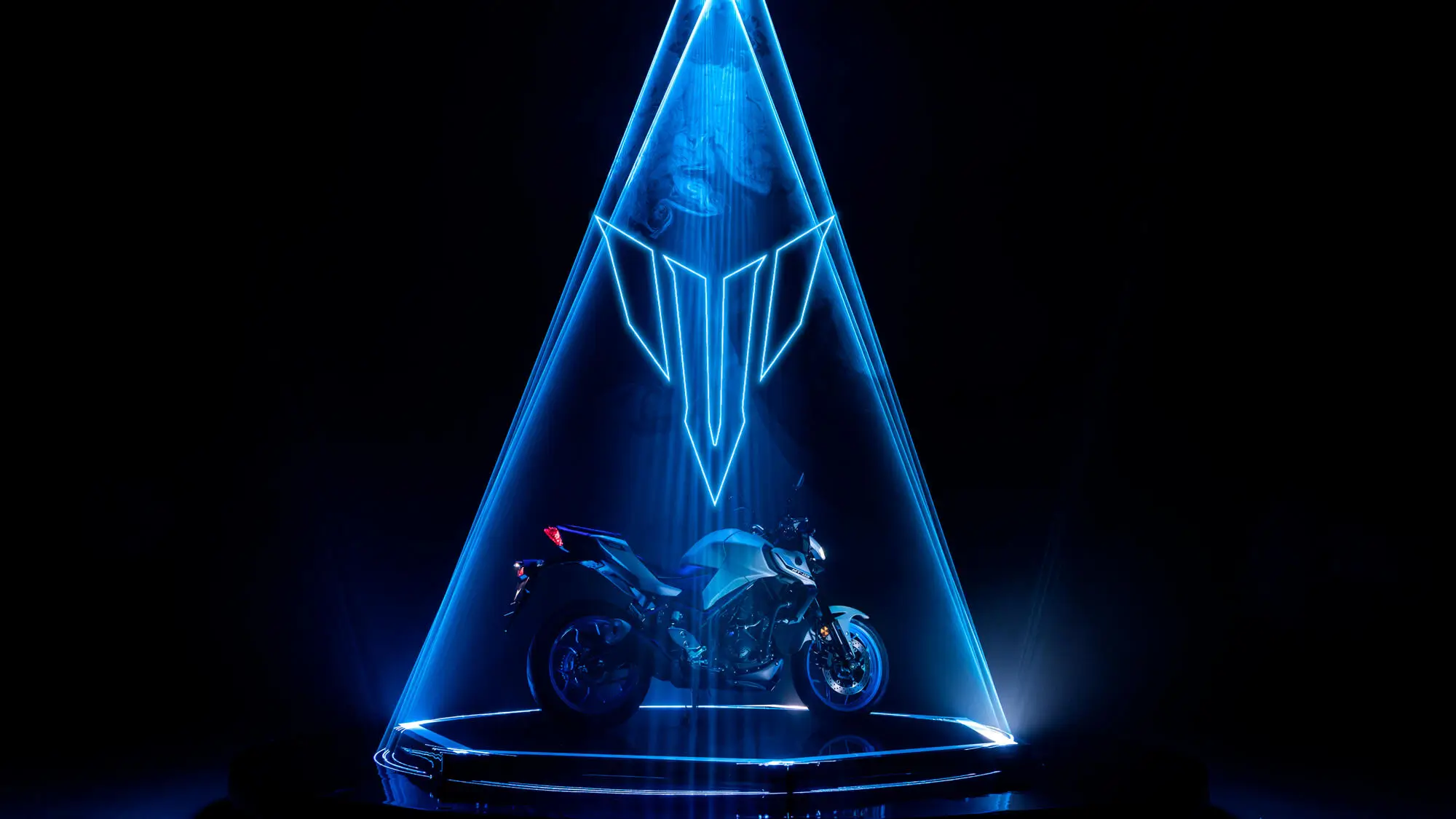 Yamaha MT-320 Motorrad in blauem Lichtstrahl auf dunklem Hintergrund.