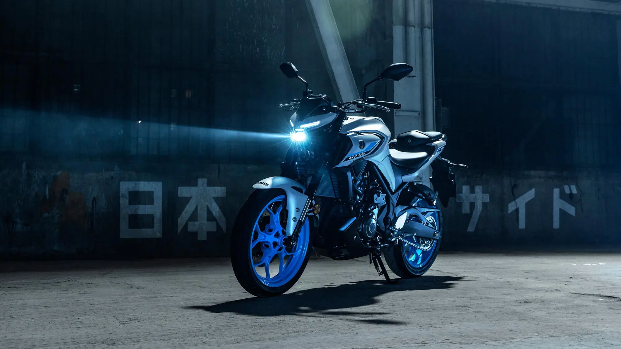 Ein Yamaha MT320 Motorrad steht in einem dunklen, industriellen Raum mit eingeschaltetem Scheinwerfer.