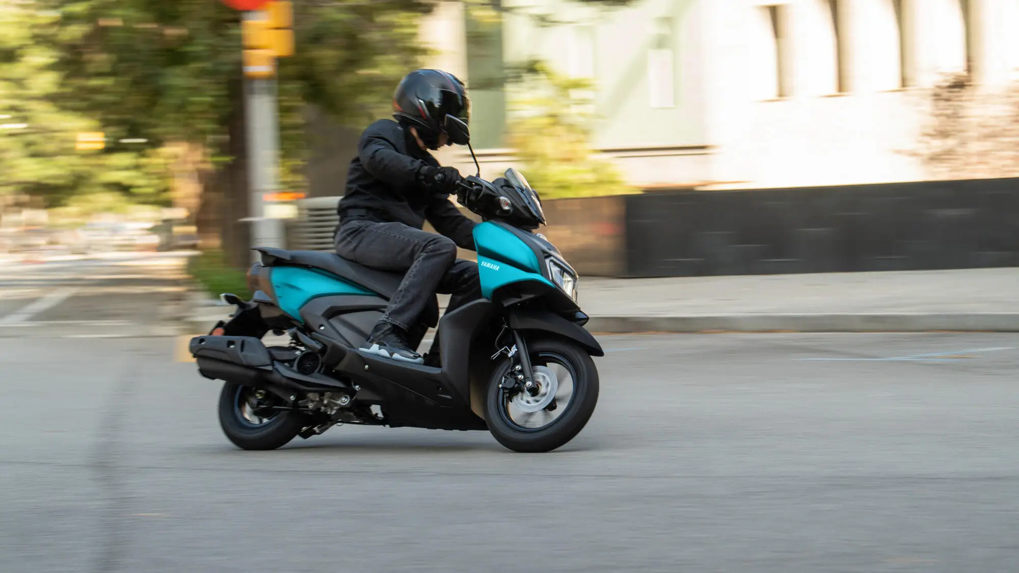 Eine Person fährt einen Yamaha RayZR Roller auf einer Straße.