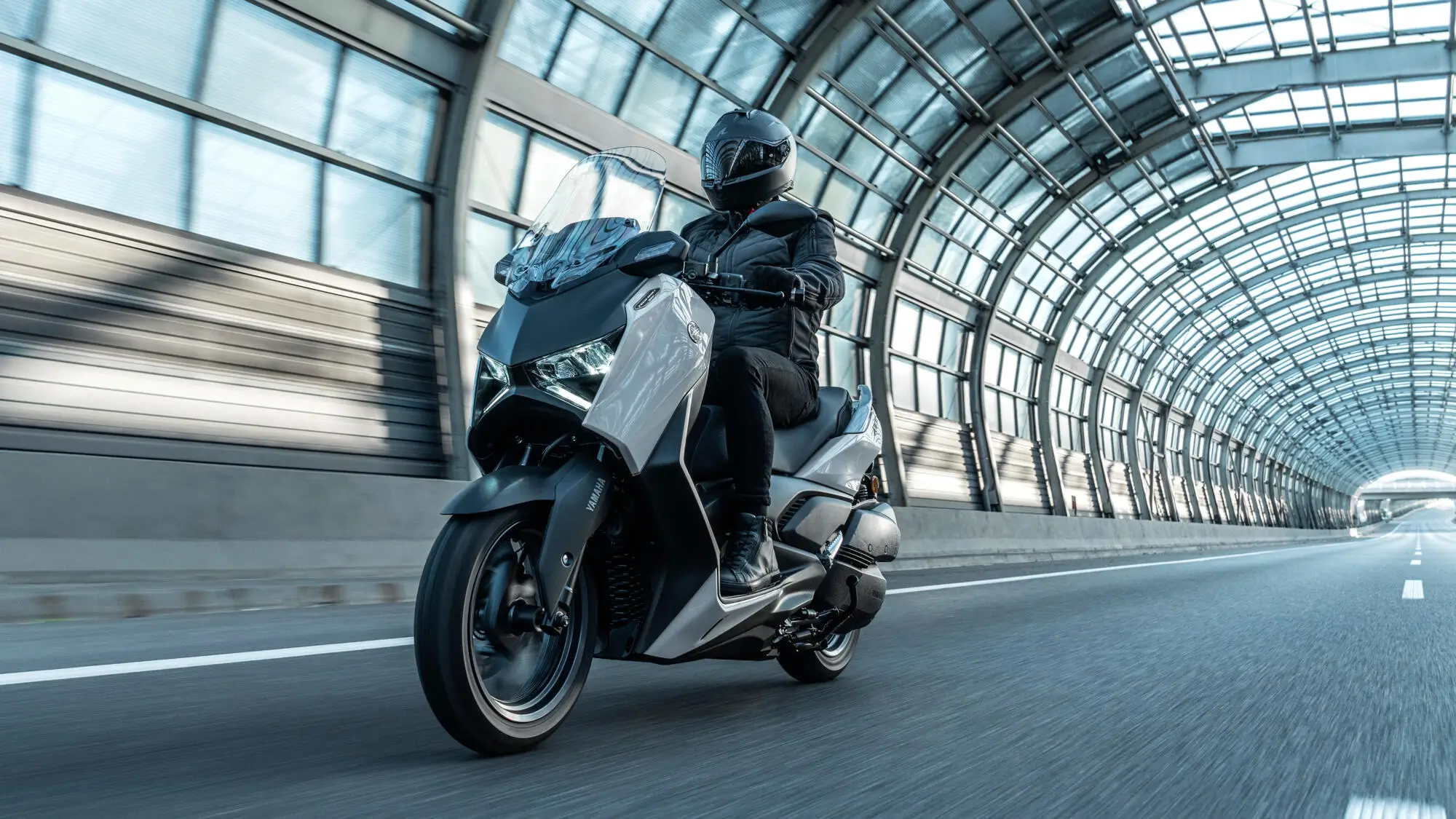 Ein Motorradfahrer auf einer Yamaha XMAX 300 Tech MAX fährt durch einen modernen Tunnel.