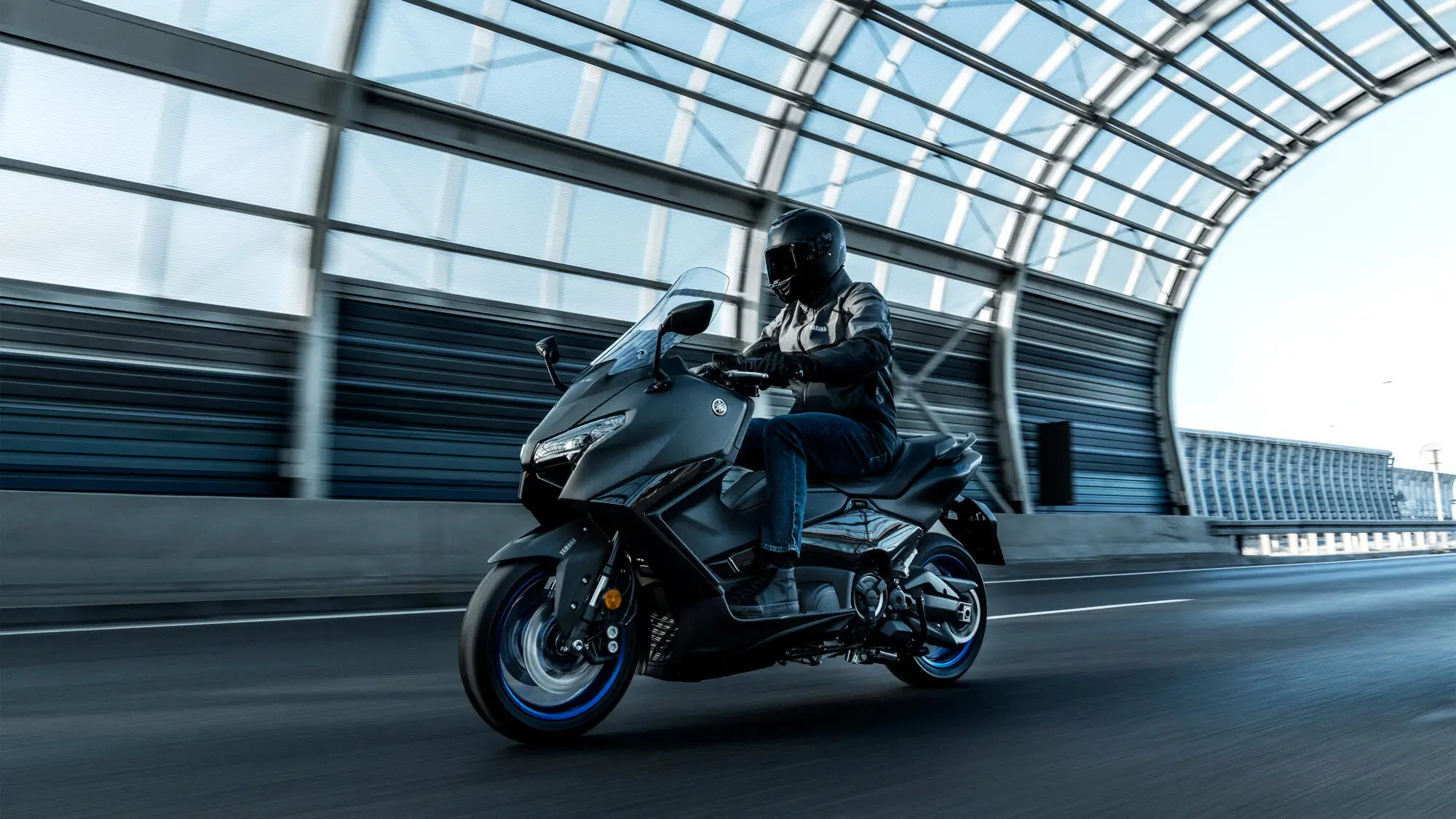 Ein Motorradfahrer fährt eine Yamaha XP500A TMax durch einen überdachten Tunnel.