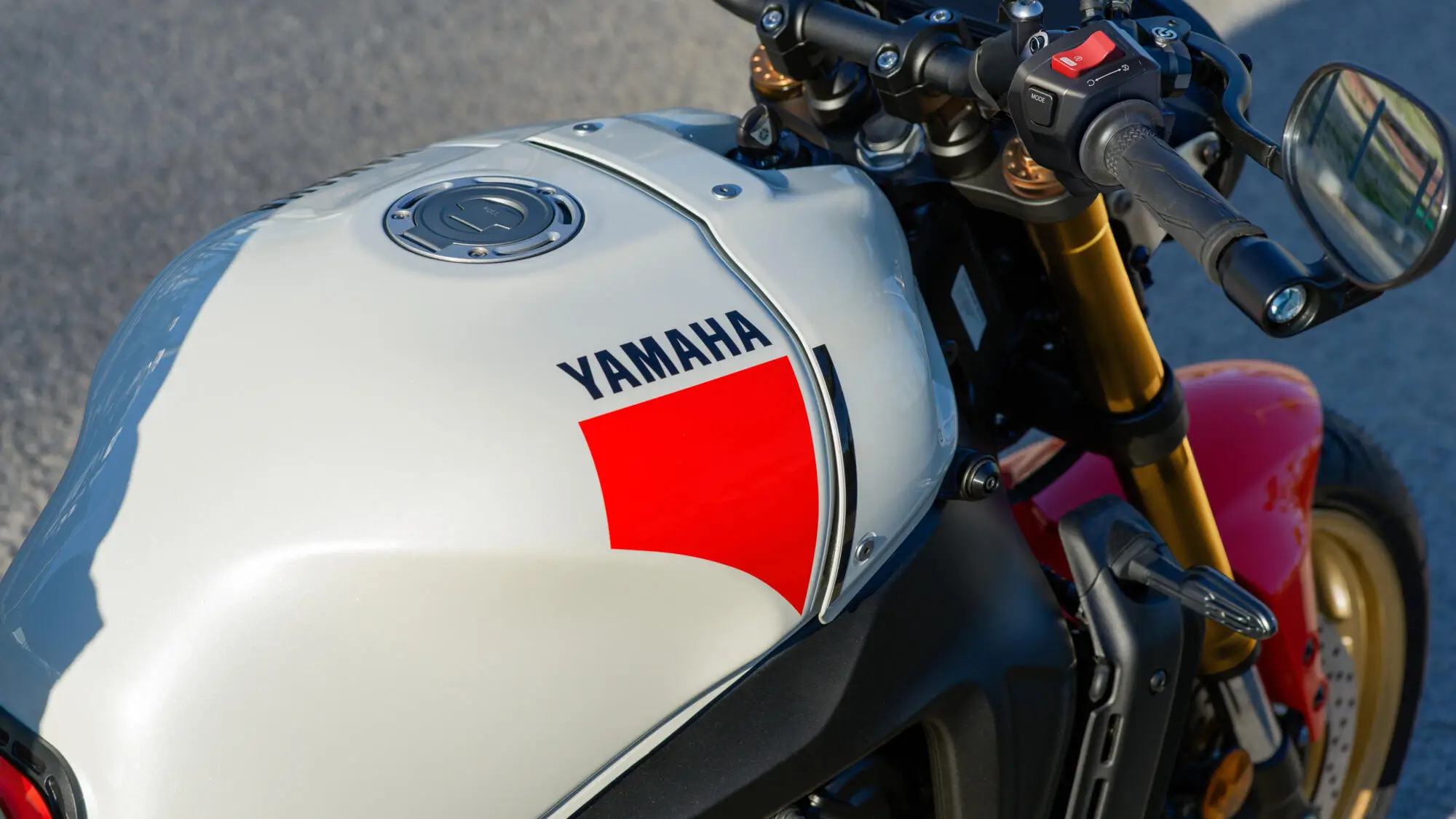 Nahaufnahme eines weißen Yamaha XSR900 Motorradtanks mit rotem Akzent und Lenker.